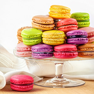 传统的法国五颜六色的马卡龙个璃蛋糕站木制桌子上图片