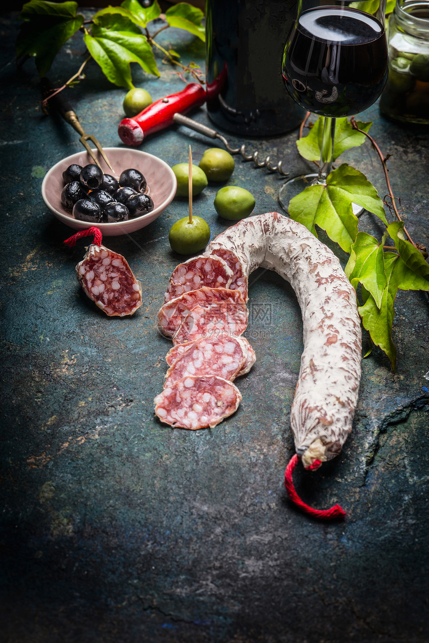 切片意大利腊肠棒与安帕斯蒂,红酒葡萄叶黑暗的复古背景意大利食物图片