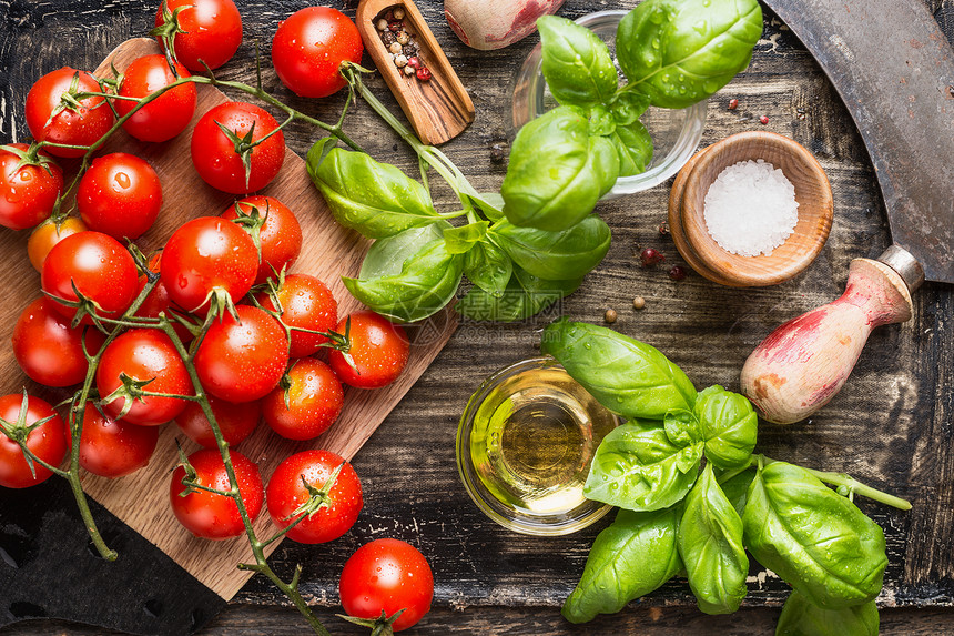 新鲜机樱桃西红柿与罗勒叶橄榄油乡村厨房桌子上,顶部视图图片