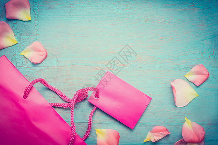特价文字素材明亮的粉红色纸购物袋与花瓣上的蓝色绿松石破旧别致的背景,顶部的视图,地方为文字,边界夏季特价出售复古风格背景