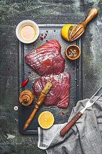 生金鱼牛排腌制与油,柠檬摩擦刷切割板,顶部视图,乡村背景,深色风格背景图片