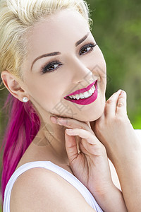 个美丽的微笑的女人女孩的户外肖像,棕色的眼睛,完美的牙齿,金色洋红色的粉红色头发背景图片