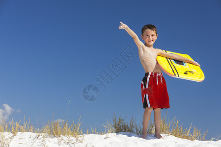 轻的男孩子,冲浪板明亮的蓝天海滩上背景图片