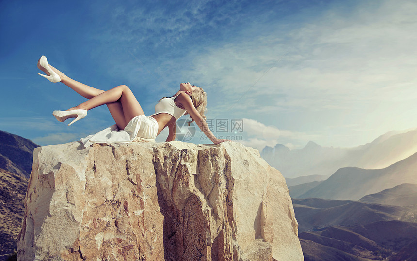 感的金发女郎锋利的岩石上放松图片