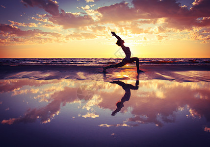 日落海滩上练瑜伽的女人剪影高清图片