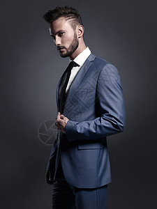 穿着优雅蓝色西装的英俊时尚男人的肖像摆姿势高清图片素材