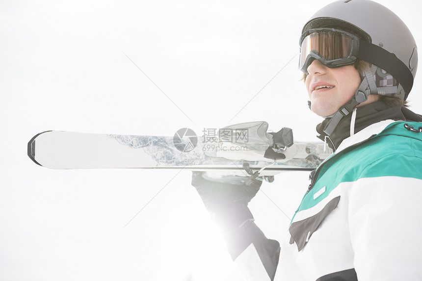 微笑的轻人,背着滑雪板,迎着晴朗的天空图片