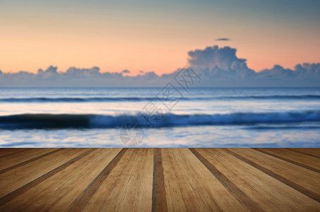 美丽的低沿海滩低潮出海与充满活力的日出天空与木制木板地板背景