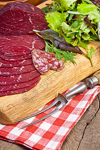 美味的意大利火腿意大利腊肠片木制砧板上,蔬菜草药烹饪传统火腿图片