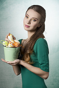 美丽,金发,清新的女人,美丽的眼睛绿色的衣服她着装满复活节鸡蛋的小水桶背景图片