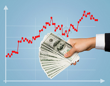 商业金融人投资财富蓝色背景外汇增长图表上,男股票经纪人手握美元现金的特写人类高清图片素材