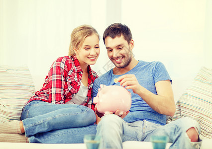 沙发上的女人金钱,家庭,金融关系的微笑的夫妇储蓄罐坐沙发上设计图片