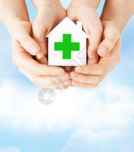 关心,帮助,慈善人的密切的手,着白纸屋与绿色交叉标志图片