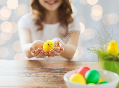 复活节,假期孩子的女孩锅与绿草,黄色鸡玩具碗彩色鸡蛋桌子上的灯光背景图片