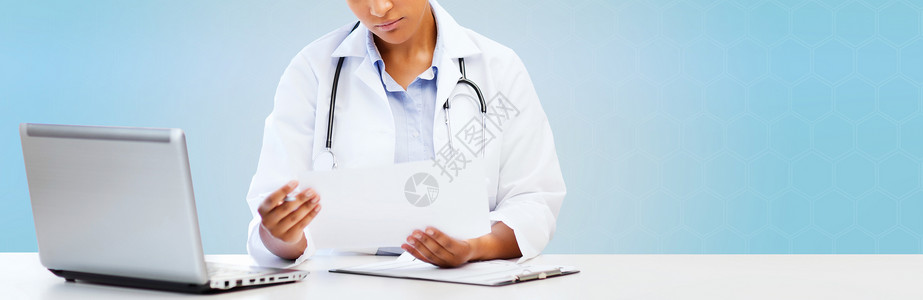 医疗保健,医疗诊断技术非洲女医生与笔记本电脑看医疗报告蓝色背景图片
