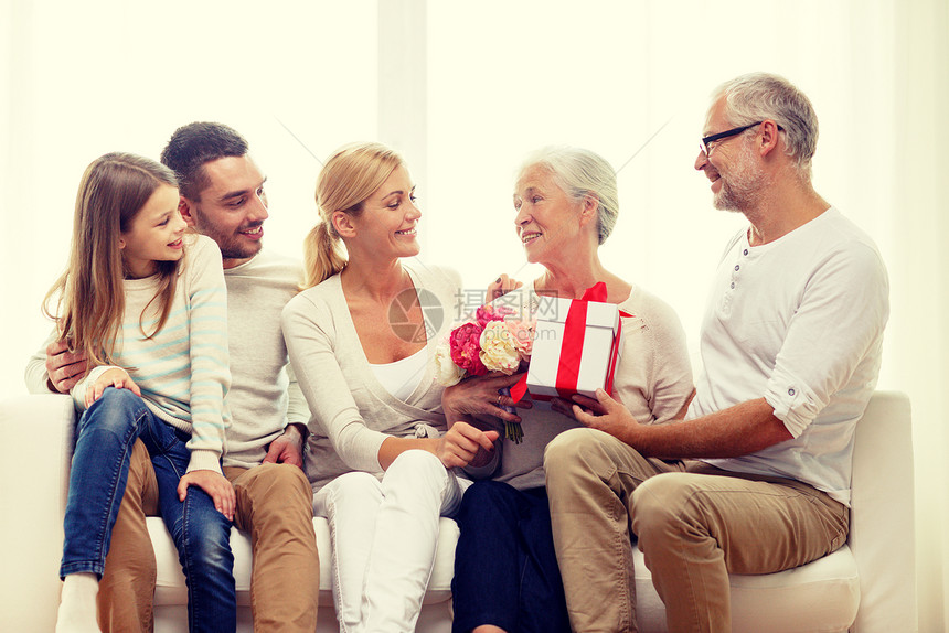 家庭,幸福,世代,假日人们的幸福的家庭,鲜花礼品盒坐家里的沙发上图片