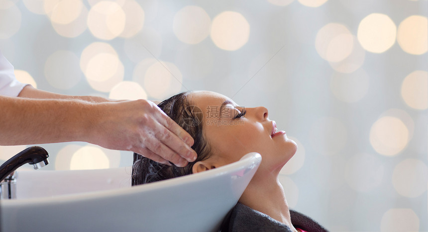 美容院,护发人的理发师洗手快乐的轻女人头上的假日灯光背景图片