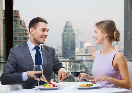 人们,饮食,庆祝,浪漫节日的微笑的夫妇与红酒食物餐厅的城市背景图片