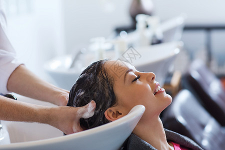 美容人的快乐的轻女人与理发师美发厅洗头图片素材