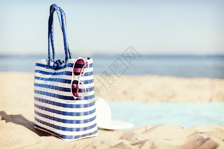帽子夏天的白色草帽,太阳镜袋子躺沙滩上的沙子里图片
