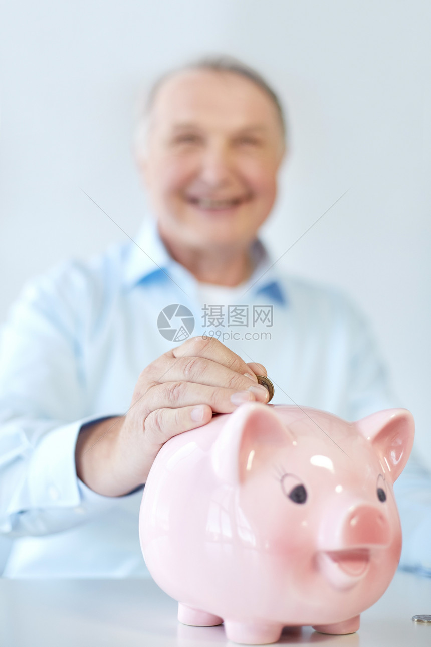 储蓄老商业人银行老人把硬币放进储蓄罐的特写图片