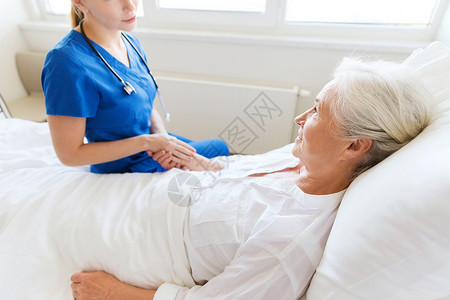 医生护士探视欢呼的老妇女躺医院病房图片