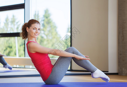 健身,运动,训练人们的微笑的女人健身房的垫子上腹部运动图片