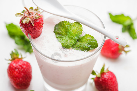 白色桌子上璃里的草莓酸奶图片