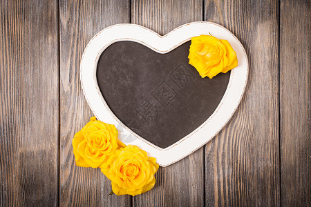 心形黑板黄色玫瑰木制背景上图片