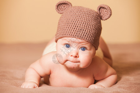 戴着熊帽的可爱宝宝躺床上高清图片