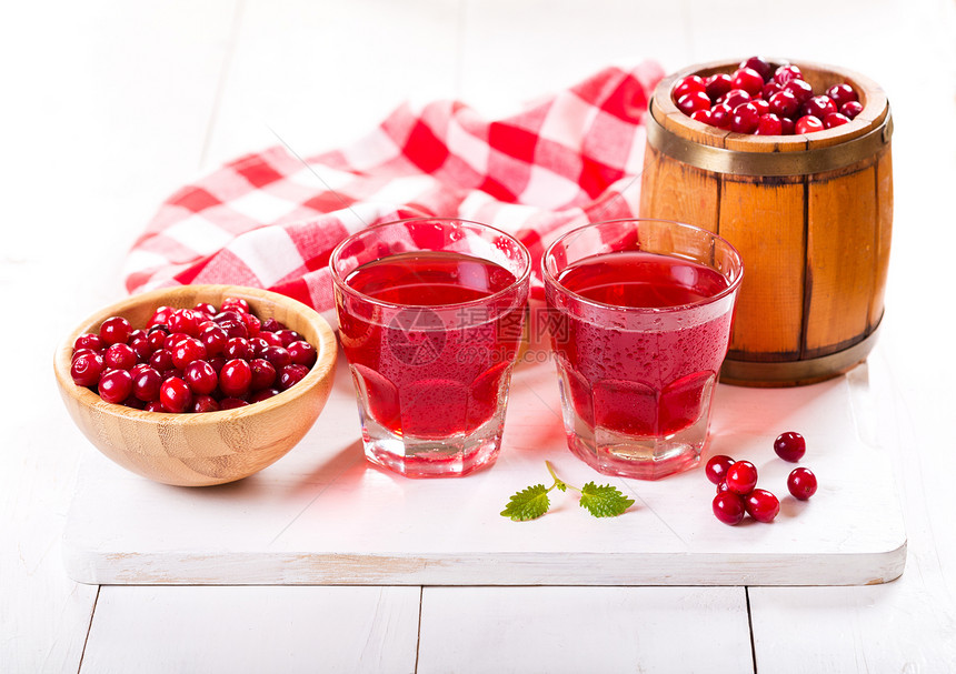 一杯蔓越莓汁新鲜浆果放木桌上图片