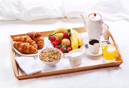 床上吃早餐托盘上咖啡牛角包谷类食品水果图片