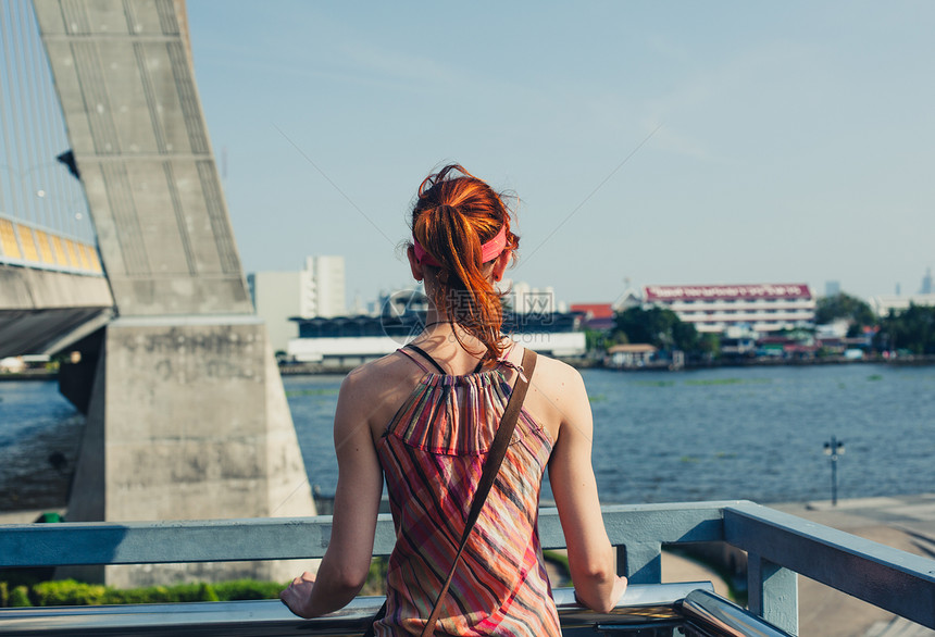 一个年轻女人站座桥上,看着座城市里的河流图片