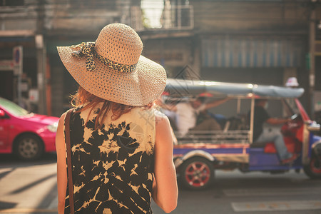 一个年轻戴帽子的女人正亚洲的街道上行走图片