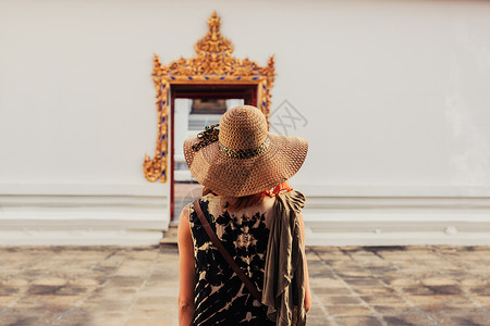 一个年轻的女人正看座佛教寺庙的精致入口高清图片