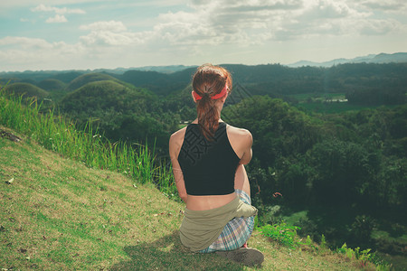 一个年轻的女人坐山坡上,欣赏着菲律宾波霍尔的巧克力山的景色图片