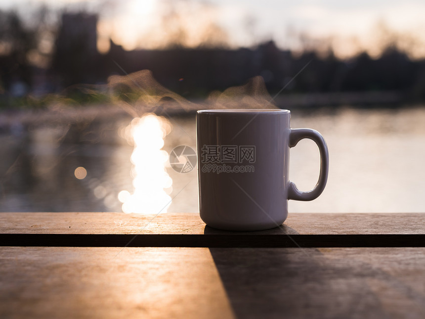 蒸汽杯子里升,冬天的日落时,池塘边杯热饮料图片