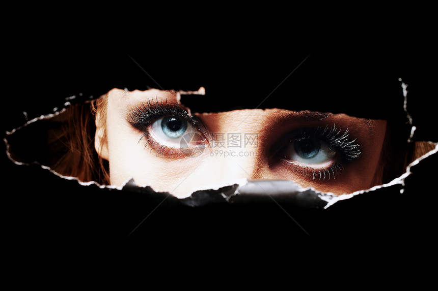 轻女人的蓝色眼睛透过个洞特写窥视图片