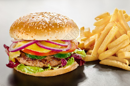个诱人的美味汉堡与红洋葱蔬菜连同美味的炸薯条的特写特写镜头沿着高清图片素材