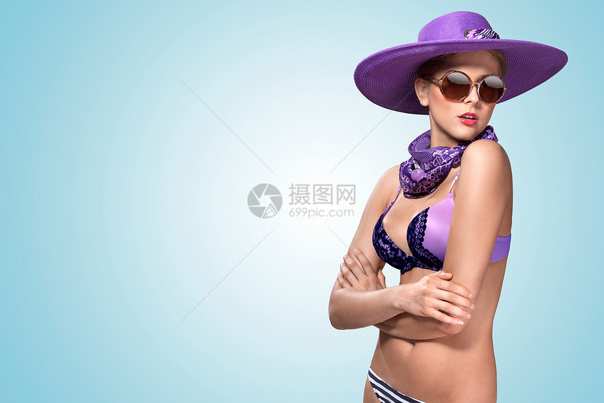 个美丽感的女孩站紫罗兰比基尼,时尚的帽子太阳镜图片