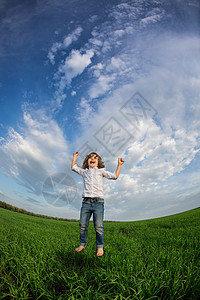 快乐的孩子绿色的田野上着蓝天跳暑假图片