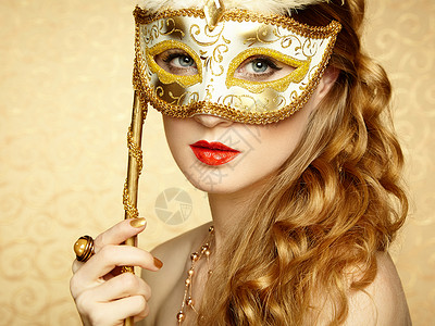 金色化妆品美丽的轻女人戴着神秘的金色威尼斯具时尚照片背景