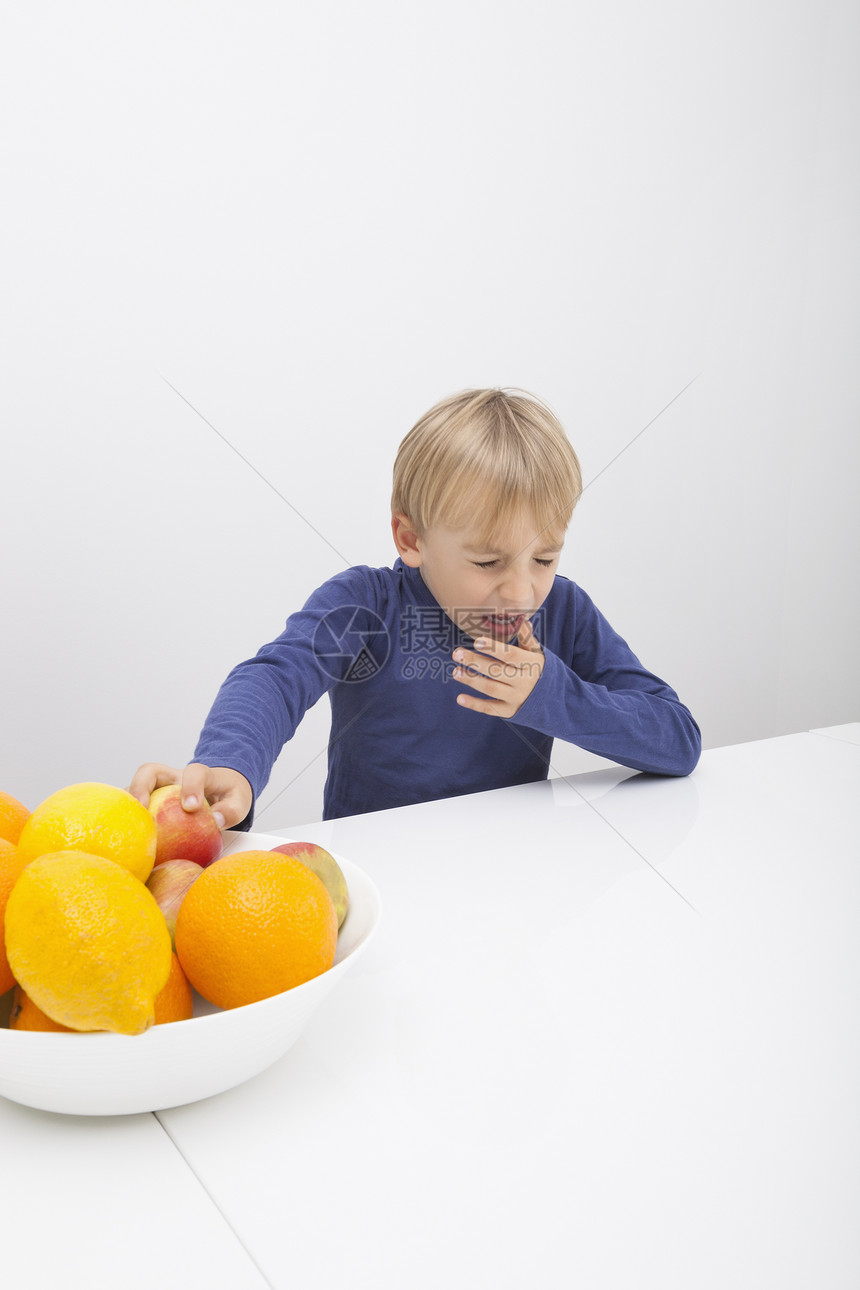 带着水果碗的男孩桌子上打喷嚏图片