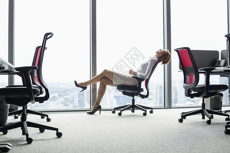 轻女商人办公室靠椅子上的完整侧视图图片