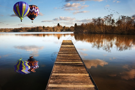 美丽的图片热气球日落景观的木制钓鱼码头平静的湖泊与清晰的反射图片