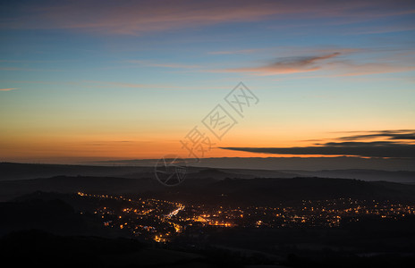 美丽的黎明前景观,俯瞰山谷中城镇的灯光图片
