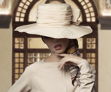 可爱的时尚镜头优雅的女人,脸上盖着大帽子,穿着米色连衣裙背景图片