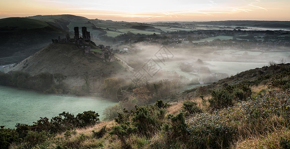 充满活力的日出中世纪的城堡遗址与雾乡村景观图片