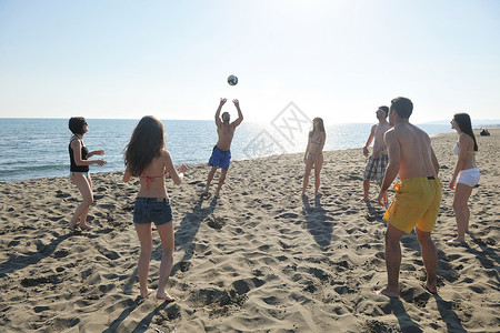 打排球的孩子轻人体玩得开心,阳光明媚的夏日打沙滩排球背景