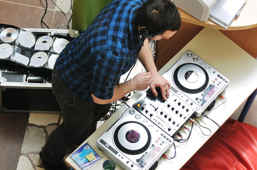 轻的DJ男子戴着耳机光盘DJ设备参加聚会图片